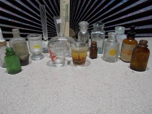 lot 107 image: The image displays a collection of vintage glass bottles and shot glasses