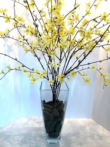 lot 56 image: Artificial Yellow Forsythia Branches in Clear Glass Vase with Black River Rocks