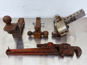 lot 65 image: Lot of Used Heavy-Duty Equipment Three Trailer Hitches (Fixed &amp Tri-Ball &amp Adjustable)And a 18 inch pipe wrench and a 24 inch pipe wrench.