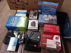 lot 176 image: Large Lot  collection of electronic networking and media hardware, including several Slingbox devices, a digital-to-analog converter box, and various routersmodems