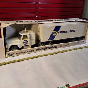 lot 315 image: Vintage Nylint NAPA Auto Parts Pressed Steel Semi-Truck and Trailer toy, often found in a white box with The standard is quality branding.