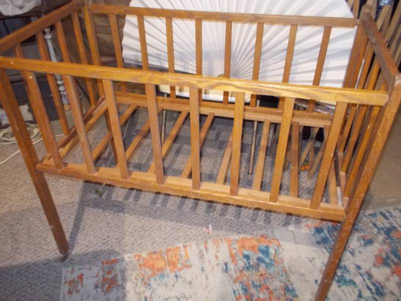 lot 23 image: This appears to be a vintage wooden baby crib or bassinet,