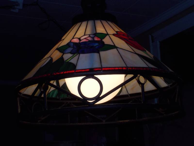 lot 30 image: This is a Tiffany-style stained glass hanging pendant light fixture with a floral motif and a wrought iron frame