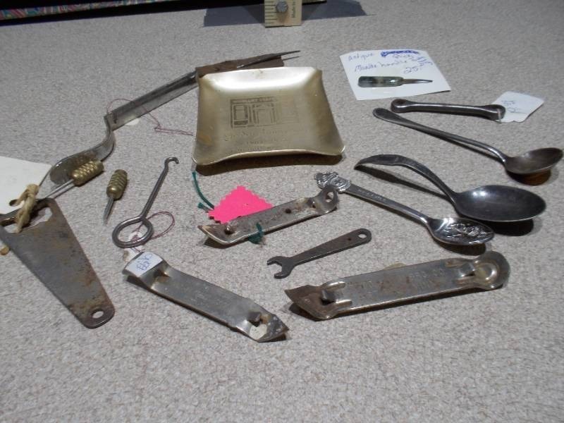 lot 104 image: several church key style can and bottle openers, spoons, and other small metal objects.