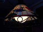 This is a Tiffany-style stained glass hanging pendant light fixture with a floral motif and a wrought iron frame
