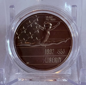 lot 92 image: 1992 P-Olympic Gymnastics Commemorative Clad Uncirculated Half Dollar - just the coin in a protective plastic case