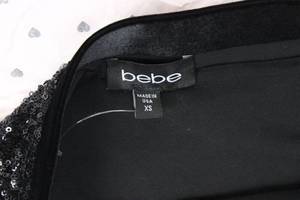 lot 53 image: GUESS Gift Bag Lot of BEBE Tops & Leather Skirts (Lot of 8)