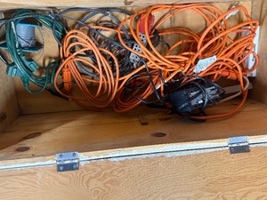 Wood box with electrical cords, battery tender and power strip.
