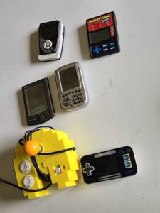 Various Vintage Electronic Gadgets Including Palm V PDA, Pocket Keno Game, and Other Handheld Devices