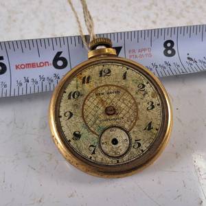 New Haven compensated pocket watch features a weathered geometric face and a gold-tone case