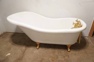 Fiberglass Slipper Clawfoot bathtub featuring polished gold-toned feet and brass hardware.