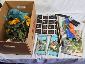 Box of Home and Garden Decor Items Including Decorative Flags, Artificial Flowers, Fabric, and Garden Tools