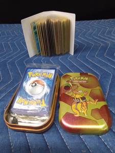 Mini book of 50 Pokmon cards and a Pokmon tin with an unopened pack of Pokmon cards