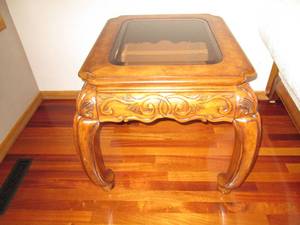 Ornate end table made of solid wood with a glass top.  Measures 28 x 24 x 28.  Matches lot 302 and 304