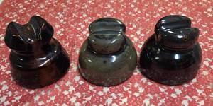 Three Vintage brown ceramic or porcelain electric line insulators, frequently used on railroad or telephone poles to prevent power lines from grounding out.  Used early-to-mid 20th century for railroad and telephone communication lines.