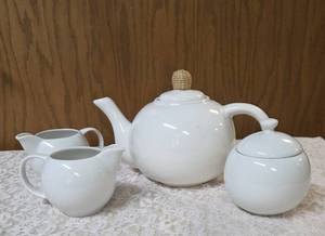 Vintage porcelain tea set featuring a teapot with a rattan handle, a creamer, and a sugar bowl, similar in style to Japanese or German postmodern designs from the mid-to-late 20th century.&nbsp&nbsp