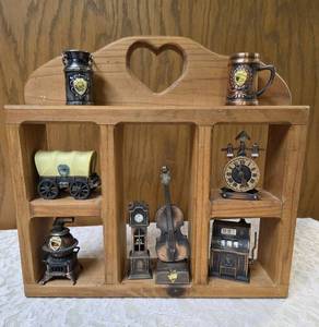 Vintage wood wall hanging shelf featuring a decorative heart cutout and die-cast metal collectibles. Cello, wagon, scale, slot machine, grandfather clock, stove which are pencil sharpeners and a cream can and mug.&nbsp
