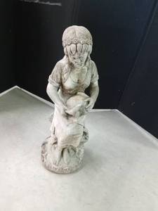Cement statue of a lady sitting on a tree stump holding a water pitcher with a basket of fruit alongside her