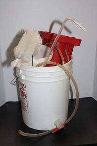 Red Plastic Fluid Pump with Clear Tubing and Cleaning Brush in Bucket
