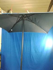 Brand New  Market Patio Umbrella. It features a dark colored canopy supported by a multi-rib metal frame structure