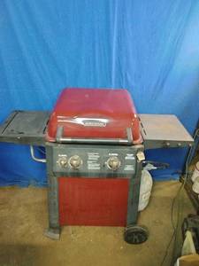 This is a red Brinkmann 2-burner propane gas grill with folding side shelves.
