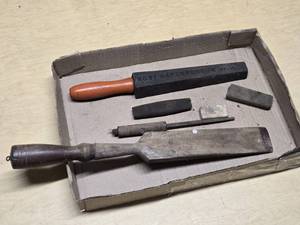 Old woodworking and sharpening tools including large Wooden chisel, sharpening stones, and honing tools