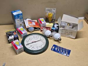 Various Light Bulbs and Wall Clock including Westinghouse Daylight Twist, EverBrite LED, and Sunbeam Anti-Insect Bulbs