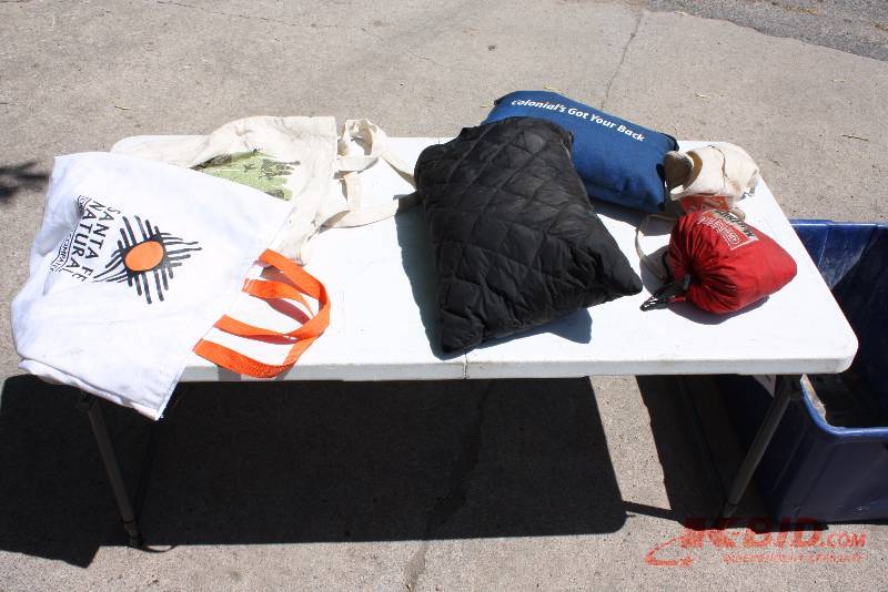 lot 44 image: Table Lot of Clothing Items Including Jackets Pants Tote Bags And More Does Not Include Table.