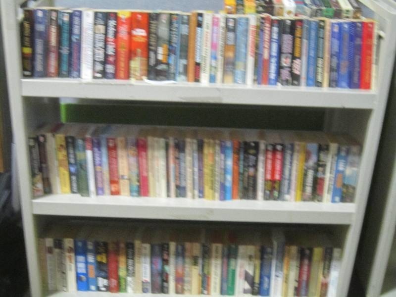 3 SHELVES OF PAPERBACK BOOKS.