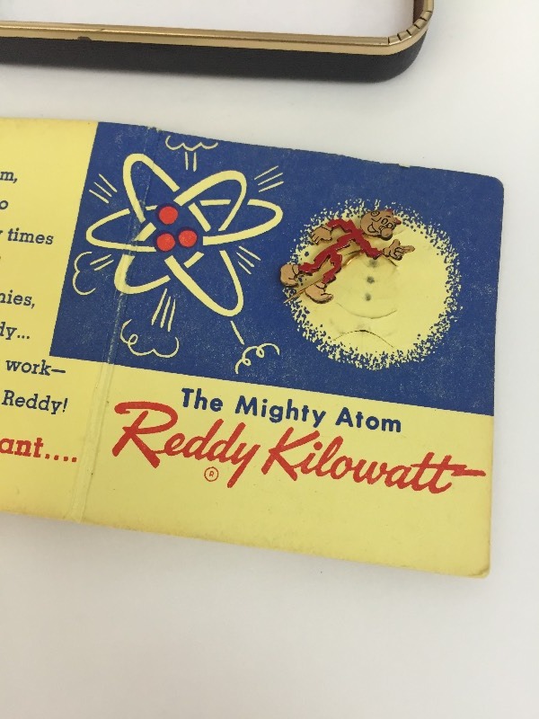 lot 7 image: Reddy Killowatt The Mighty Atom Lapel Pin on original paper, in a case