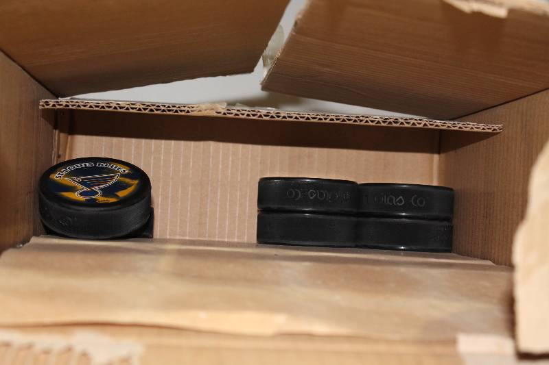 lot 824 image: Box Lot of Hockey Pucks wSt. Louis Blues Logo.