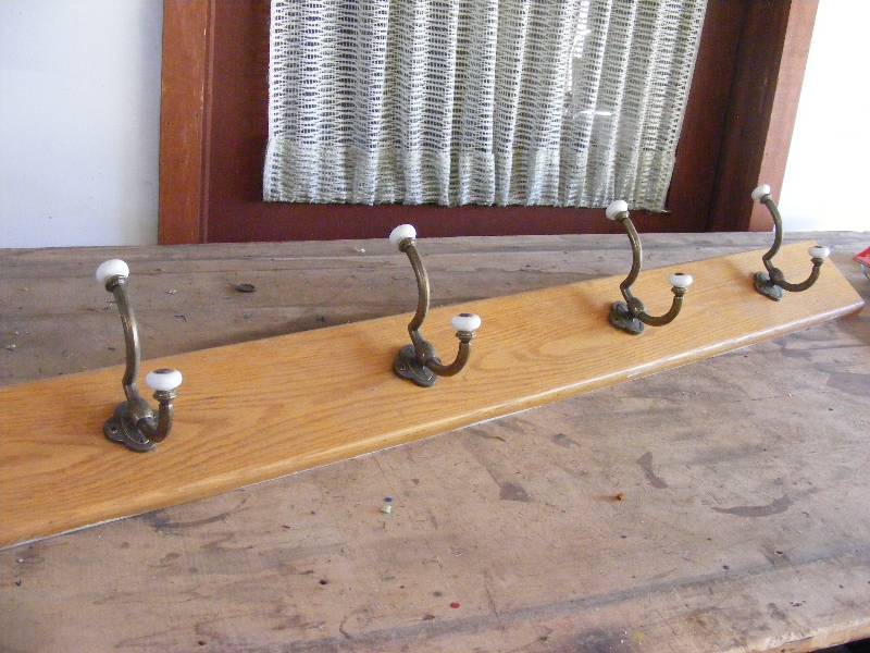 Row of 4 clothing hooks on wood.