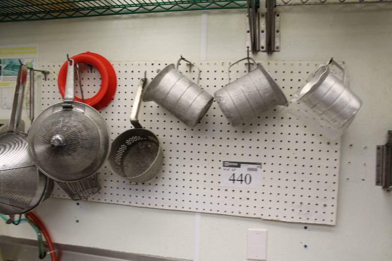 lot 440 image: Wall Lot Including Metal Measuring Cups wHandles Metal Strainers wHandles And More.