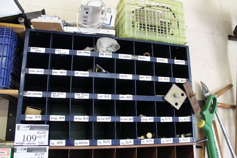 lot 109 image: Organizational Unit wMultiple Cubbies For Hardware Storage Includes Contents L-Brackets, Sign Bolts, Coat Hangers, And More.