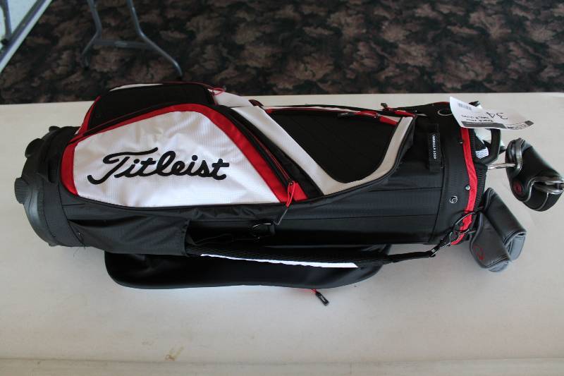 lot 34 image: Golf Lot Including Titelist Golf Bag V-Line Tank Putter Versa 2-Ball Putter Ray Cook Sivler Ray SR 300 Putter And More Brand New Condition.