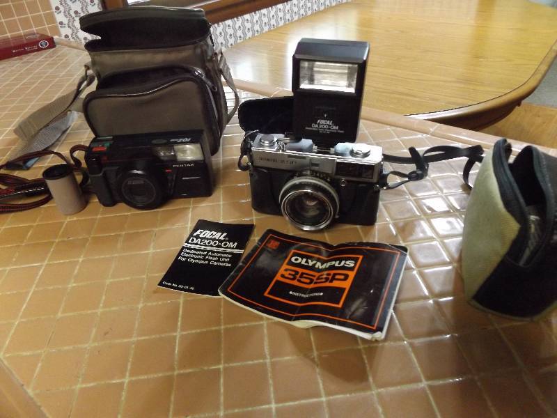 Olympus 35-SP camera with flash unit and cases, Pentax IQZoom camera with bag and film.