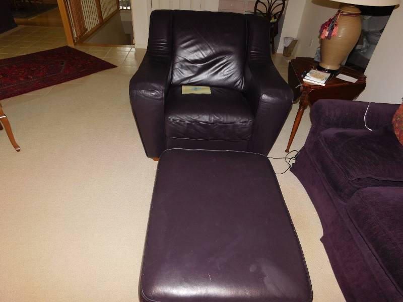 lot 2 image: Dark brown leather chair and matching ottoman.