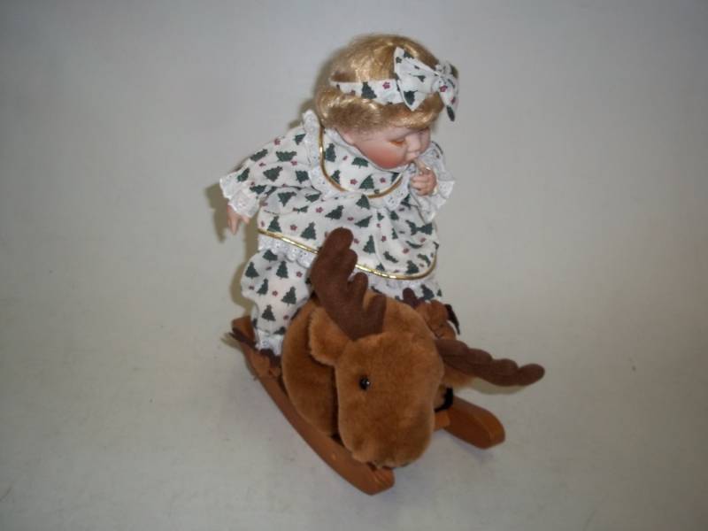 lot 243 image: 13 in Christmas Porcelain Doll with Rocking Moose