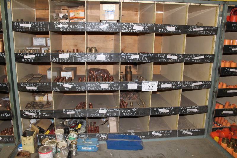 lot 122 image: Storage Shelf wMultiple Compartments & Contents Male Adapter 1.25 x 1.25 Male Adapter 1 x 1 And More 70 x 43 x 75 Includes Miscellaneous Items On Floor.