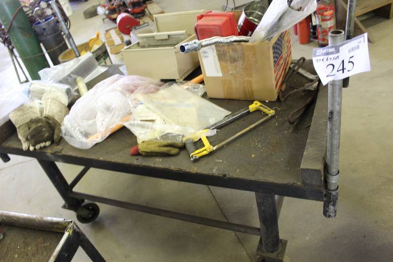 lot 245 image: Custom Metal Work Table wCorner Pipes & Wheels Includes Contents Hack Saw, Box Of Hardware, And More 34 x 67 x 28.