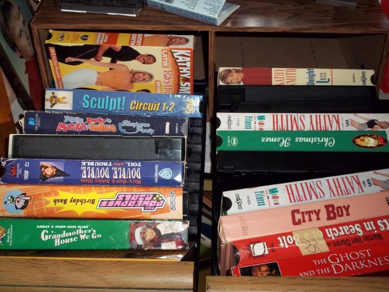 lot 39 image: Shelf of VHS and Board games with VHS holder and misl contents.